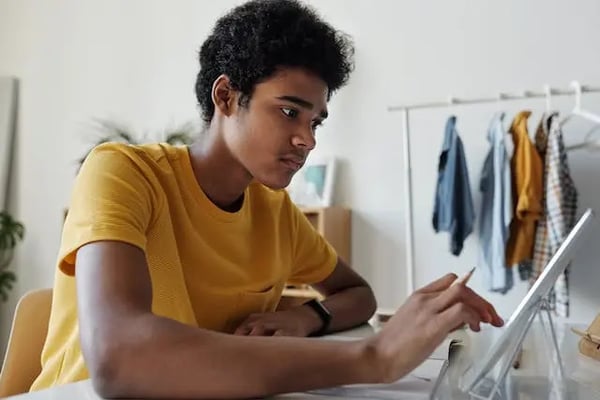 Man in yellow crew neck using tablet